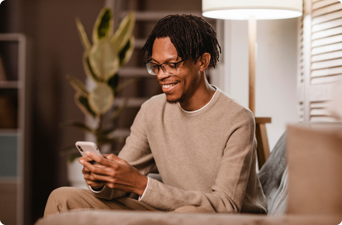 homem usando smartphone moderno sentado no sofá em casa